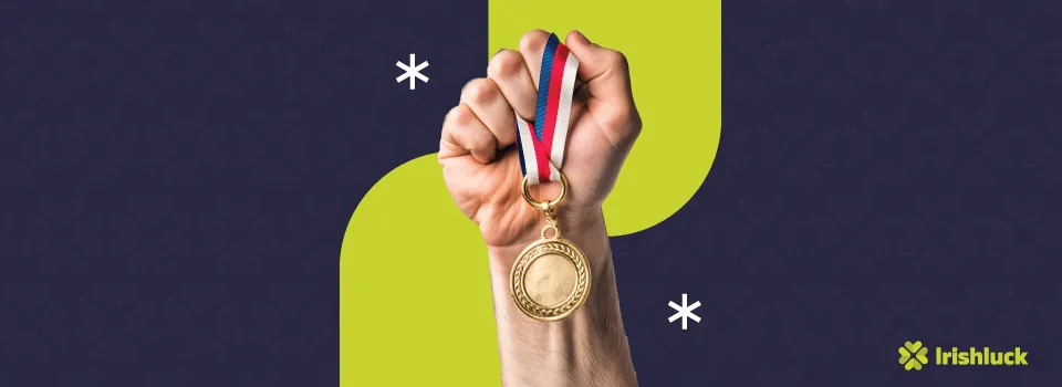 hand holding a gold medal featuring the irishluck logo on a blue background